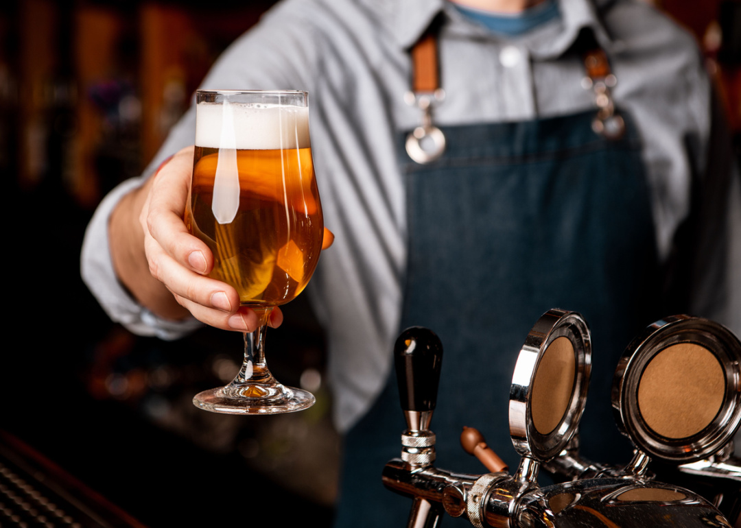 Bartender handing glass of beer across bar.