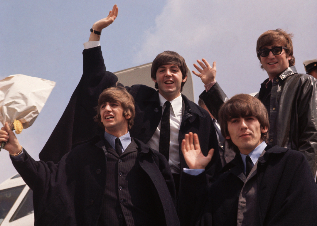 The Beatles wave from an airplane in London.