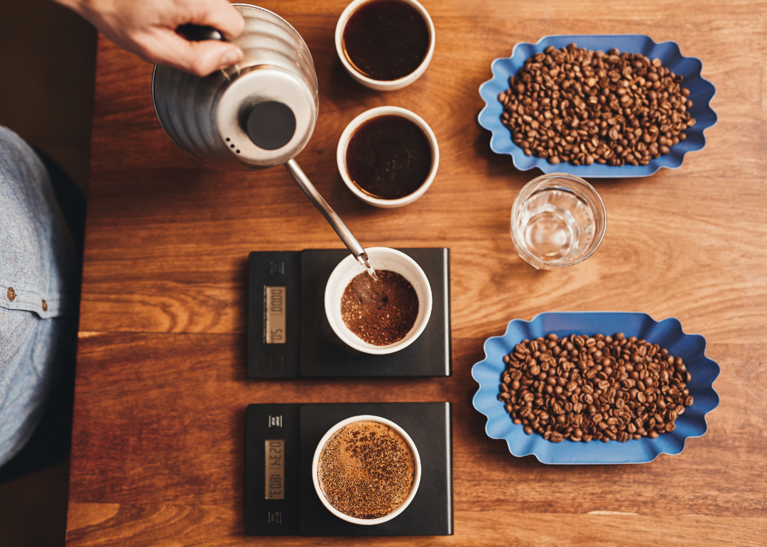 Barista pouring water into cup of ground coffee on scale