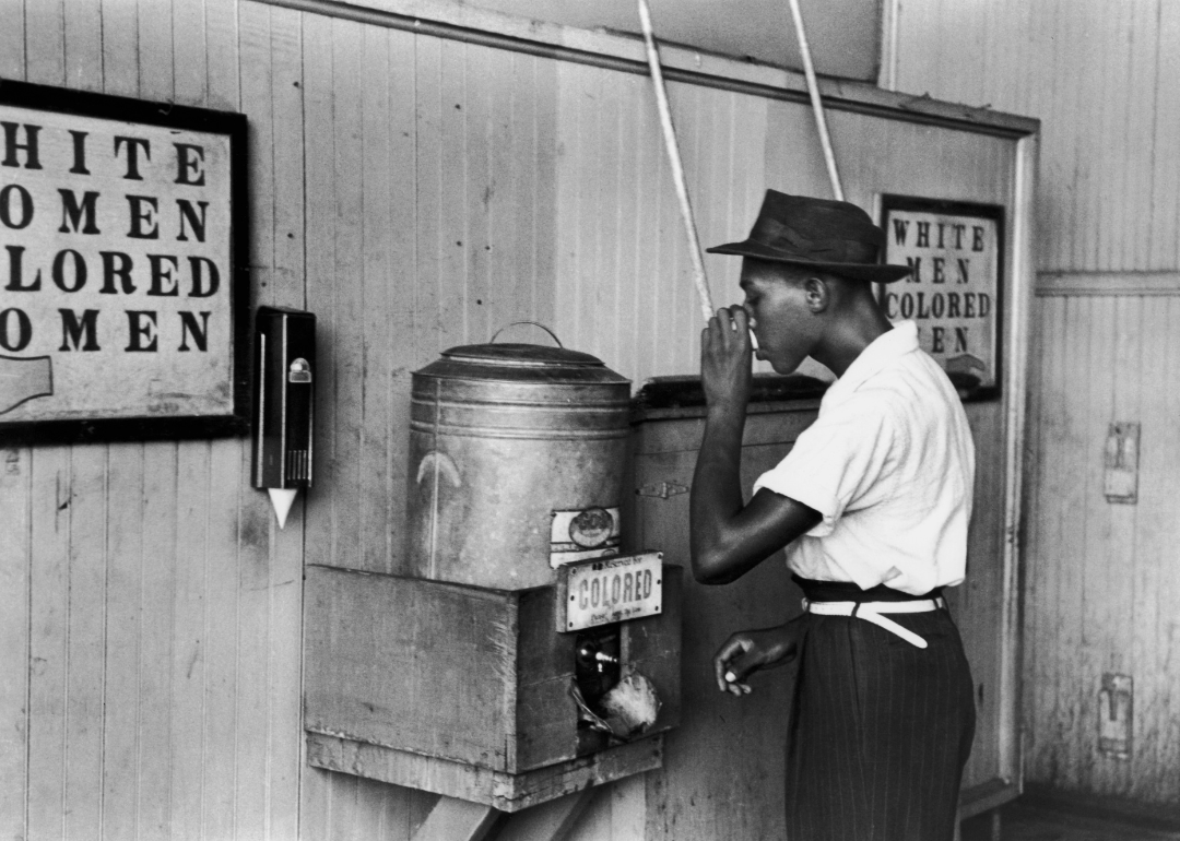Man drinking at a segregated fountain.