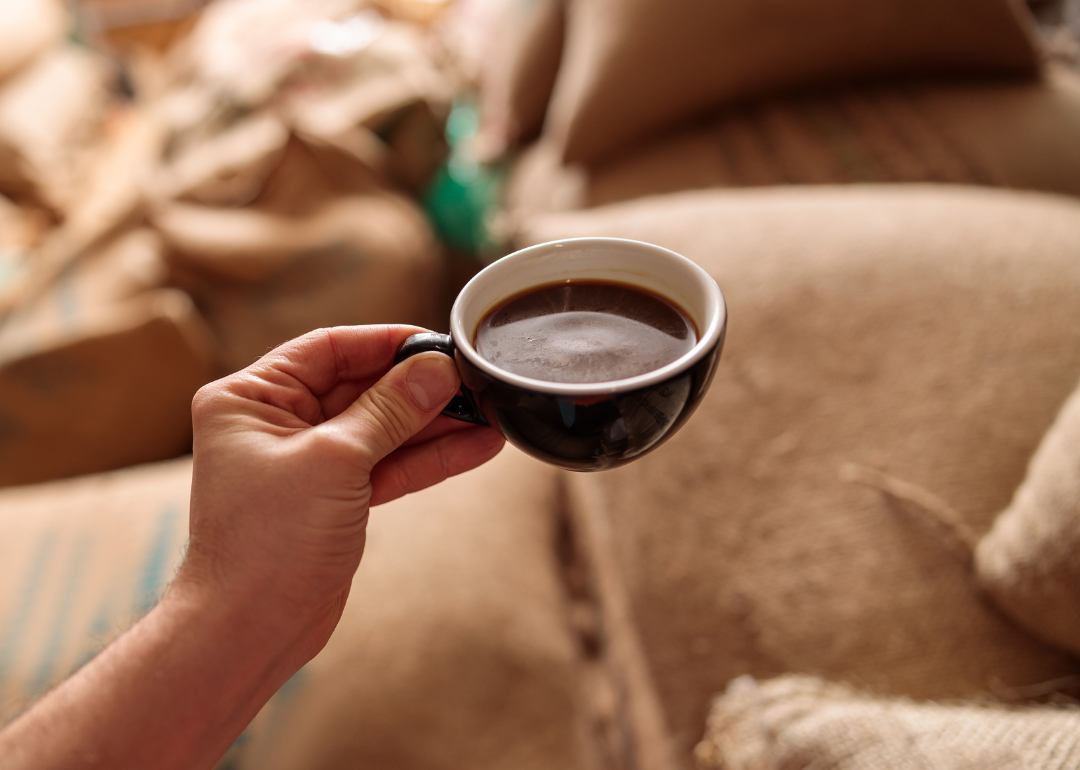 Hand holding cup of fresh roasted coffee.