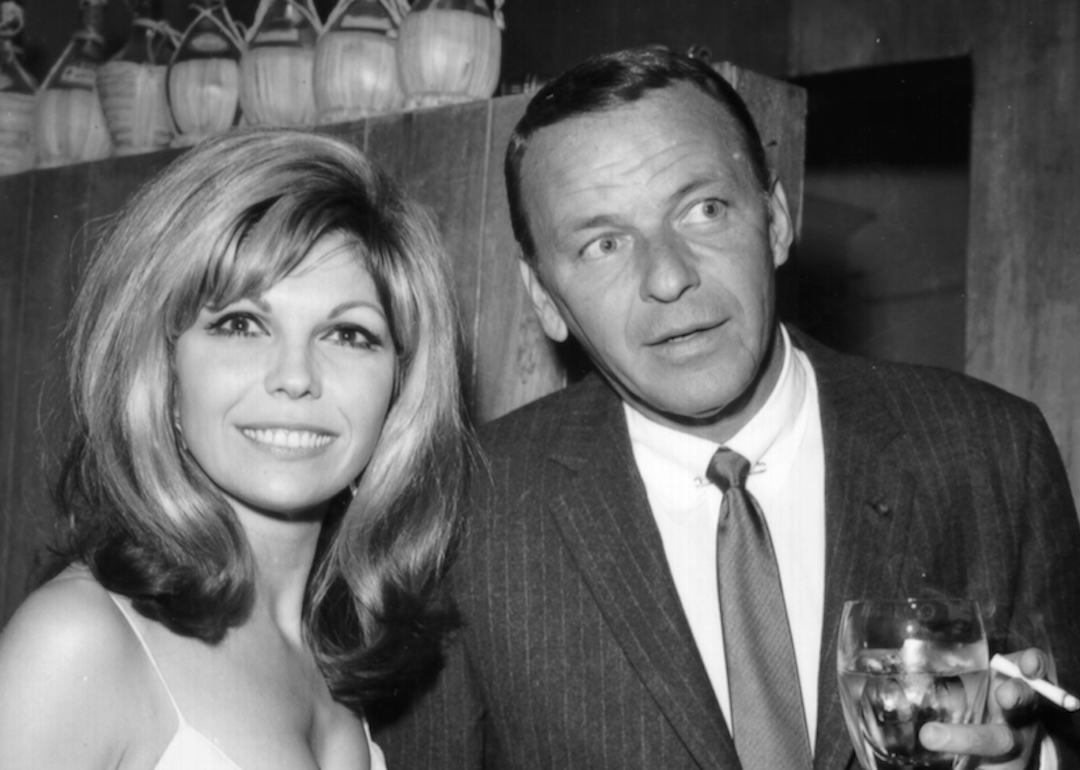 Pop singer Frank Sinatra enjoys a cocktail at an event with his daughter singer Nancy Sinatra in circa 1967.