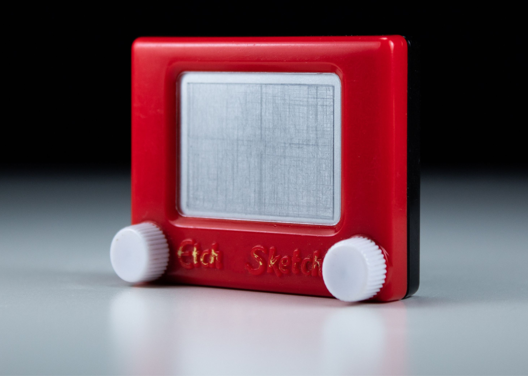 Vintage Etch A Sketch with red frame and a knob on each side on black background.