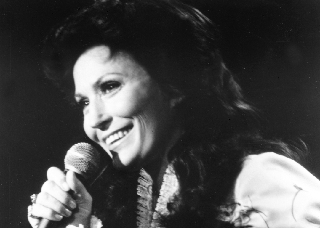 Loretta Lynn performs onstage with a microphone in circa 1975.