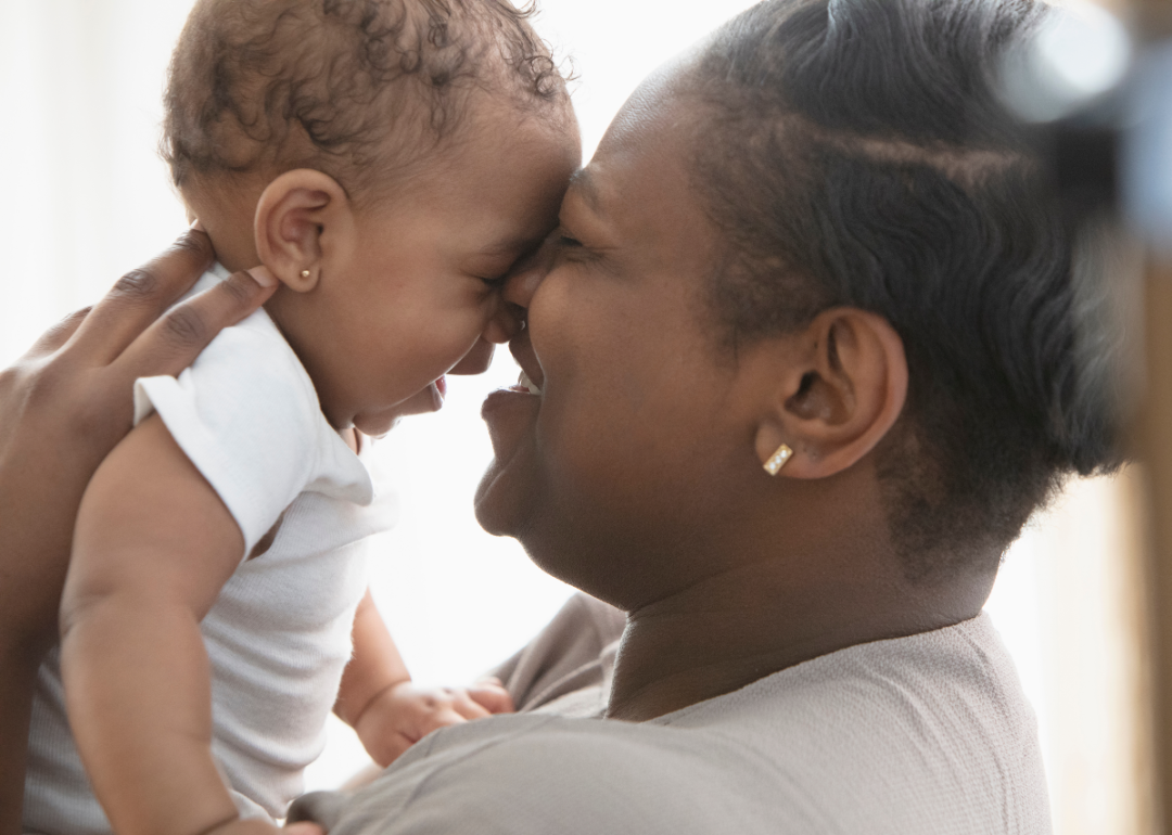 Parent goes head to head with baby and smiles.
