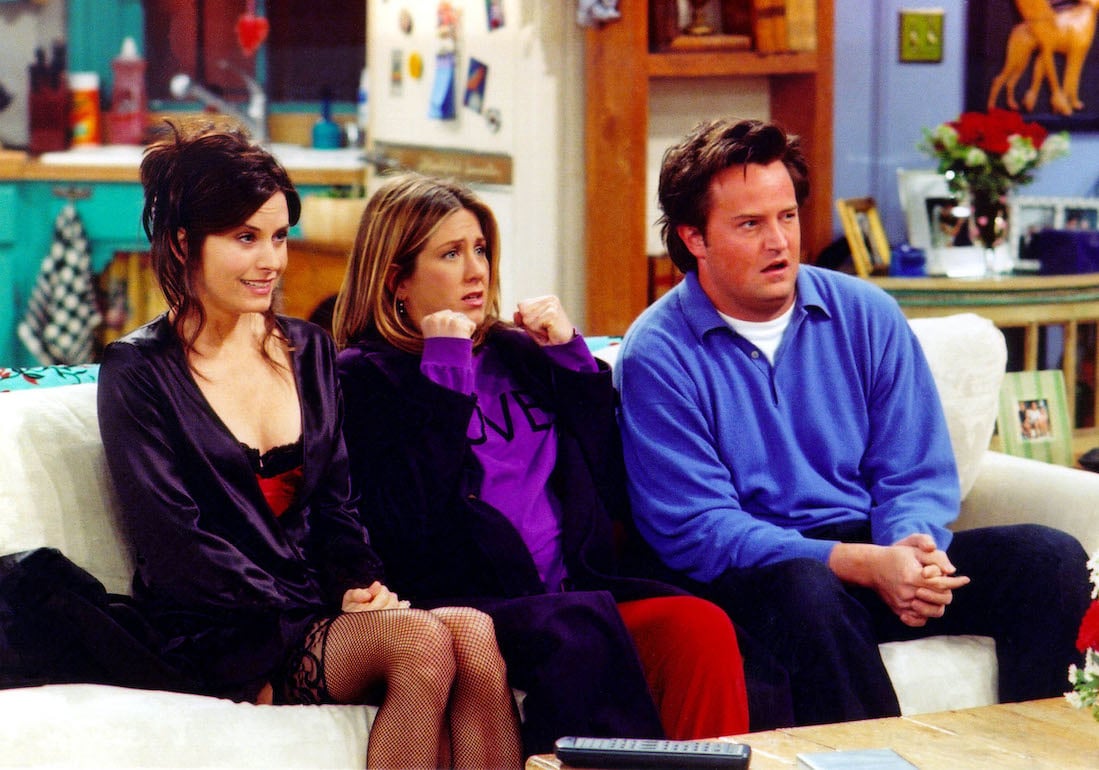 Monica (Courteney Cox), Rachel (Jennifer Aniston), and Chandler (Matthew Perry) sit on the couch in Monica and Rachel's apartment on 'Friends.'