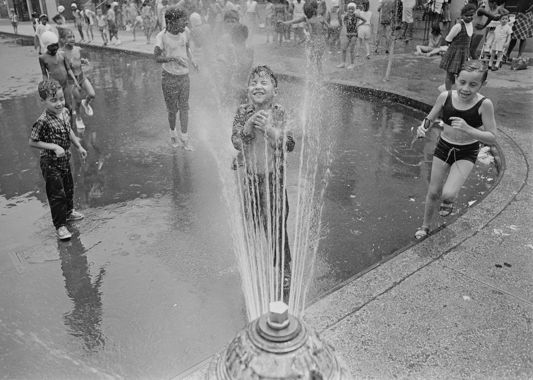Children keep cool in the spray from a fire hydrant in Harlem, New York City in August 1966.
