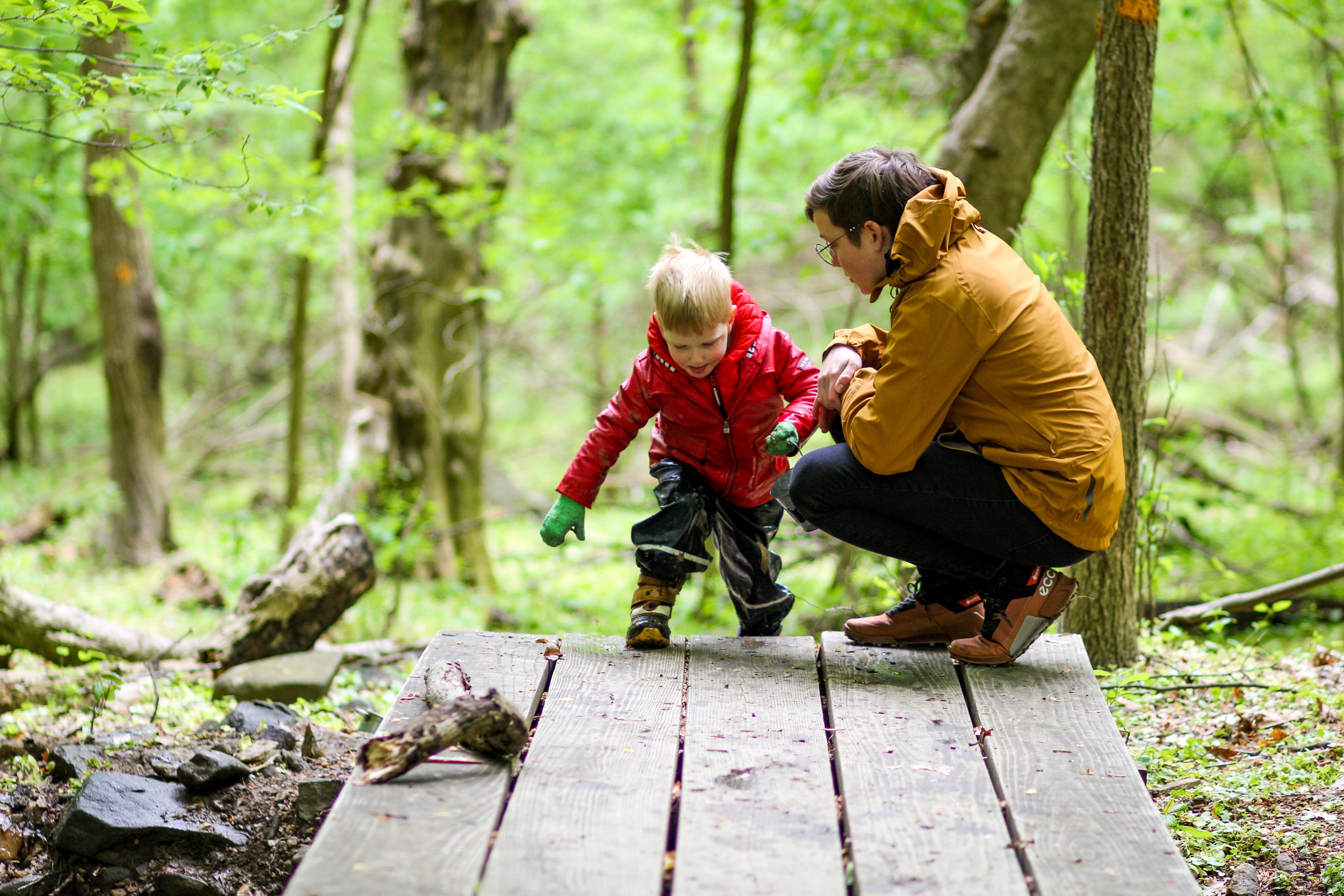 An adult helps a child step up onto a wooden platform