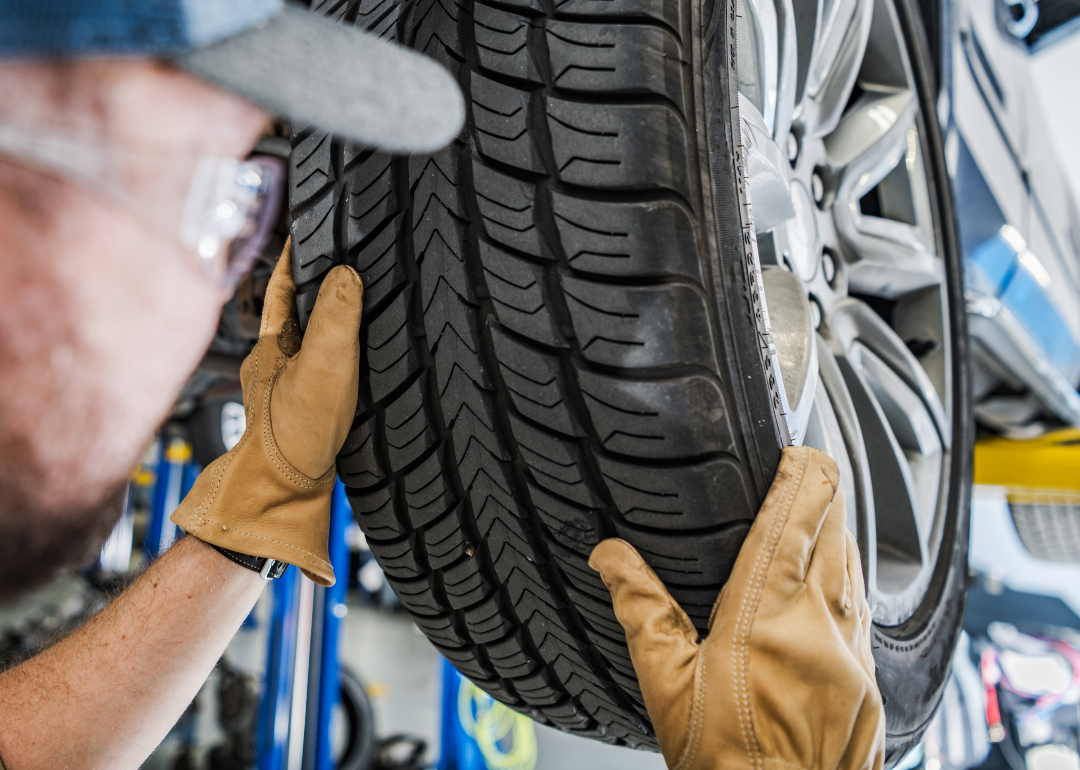 A mechanic rotates the tires on a car.