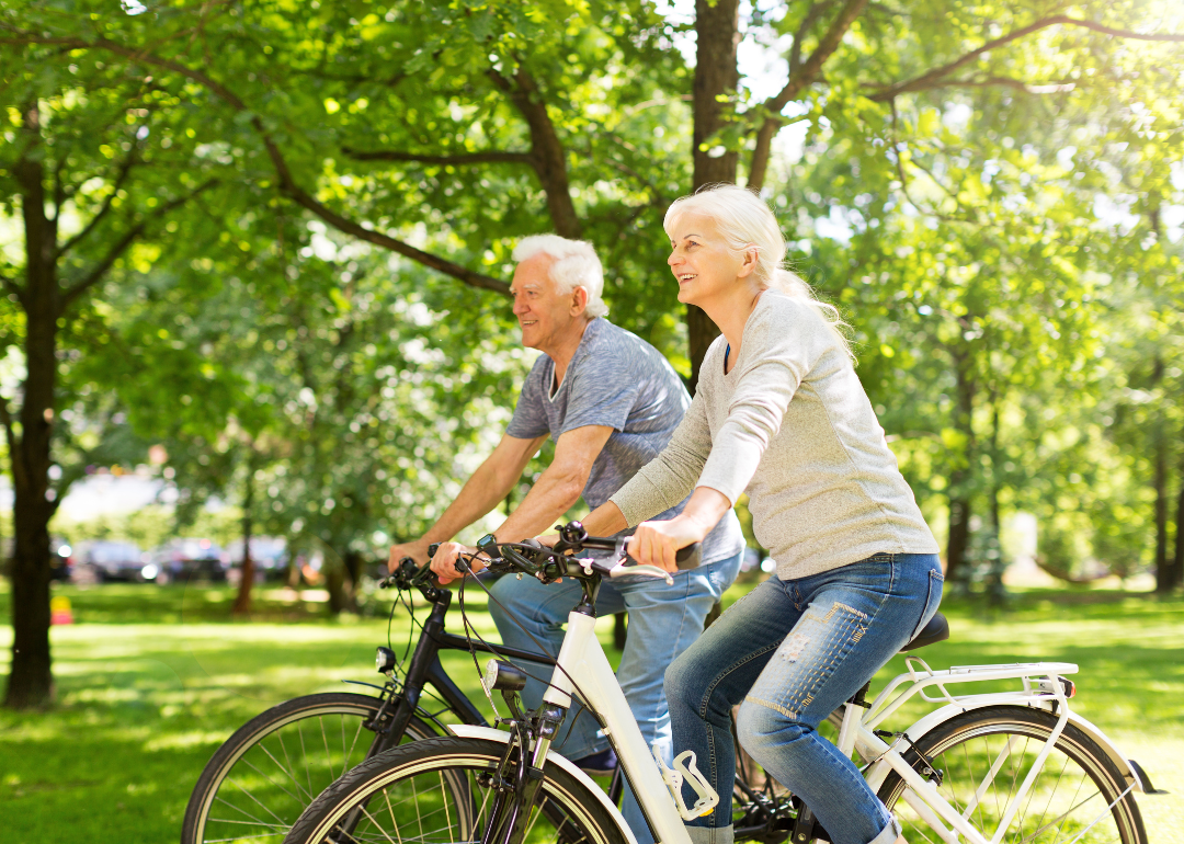 Senior couple biking through a lush green park