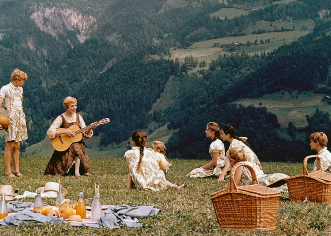 A scene from "Sound of Music" where Julie Andrews as governess Maria performs a musical number with the Von Trapp children with mountains in the backdrop