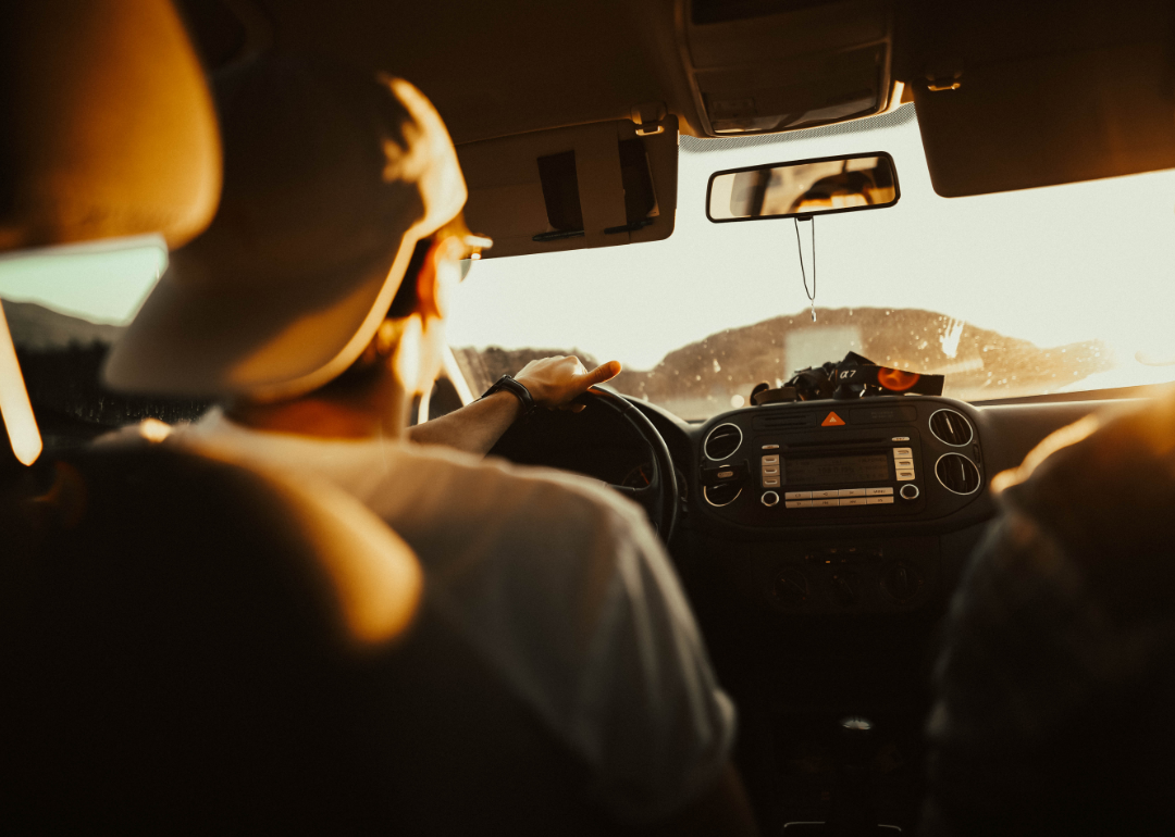 A man holding a hot steering wheel in side a car.