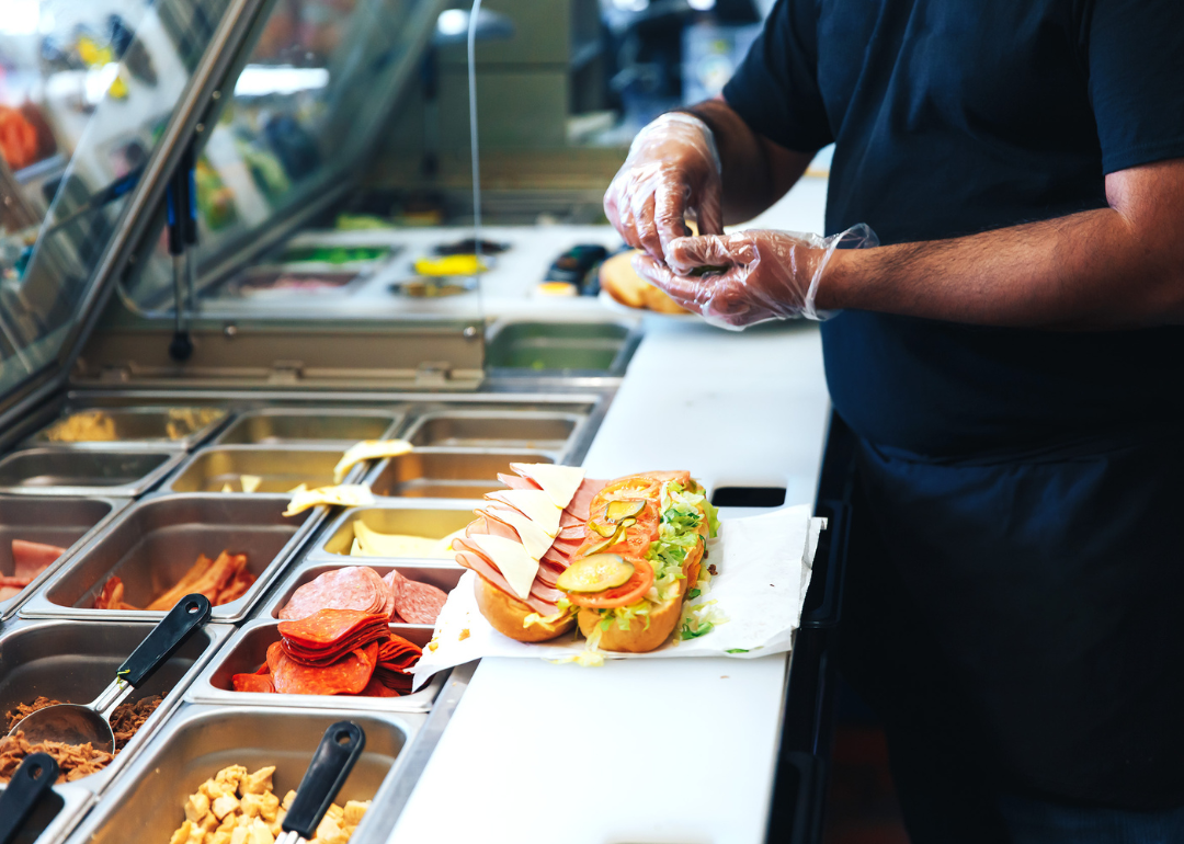 Food preparation worker prepares a sandwich at a fast food restaurant counter