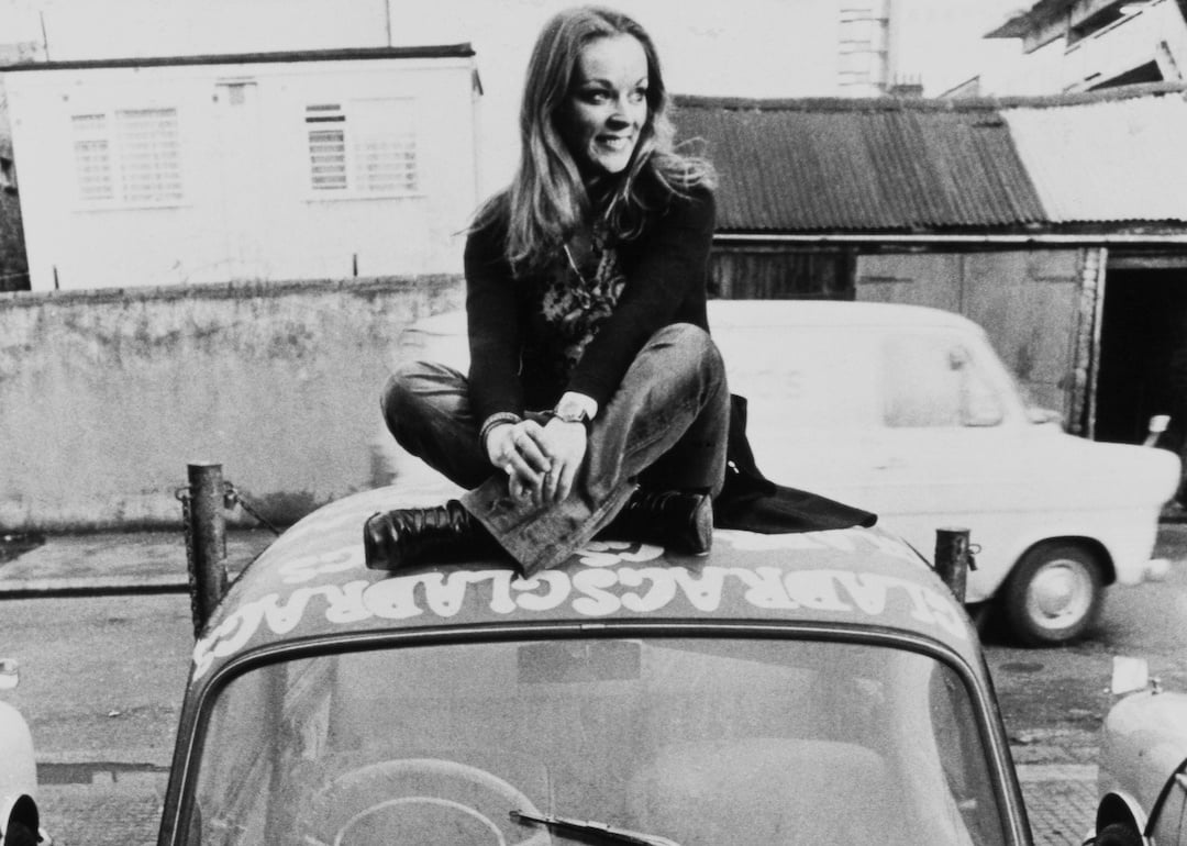 Yvonne Freeman sits on the roof of her psychedelic car.