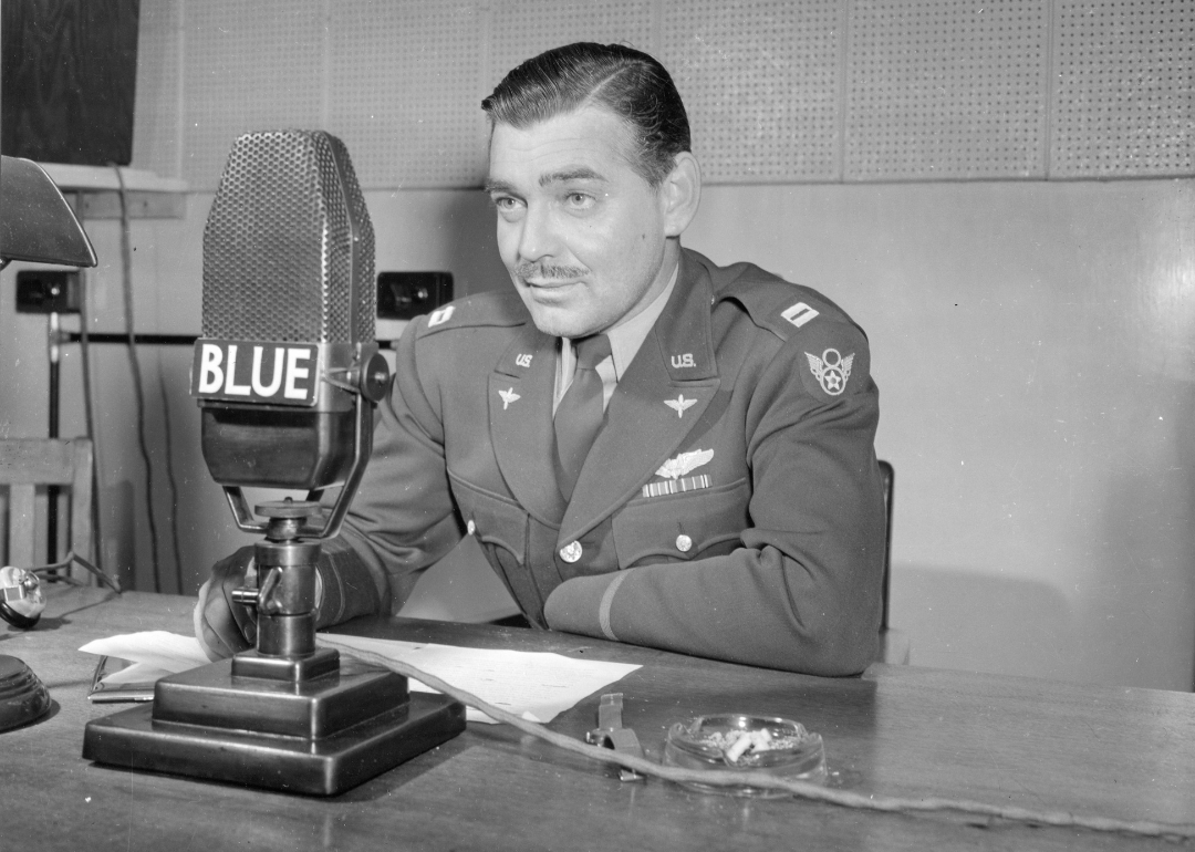 US Army Air Corps Capt Clark Gable (1901 - 1960) speaks into a microphone at a desk in a military uniform, 1943
