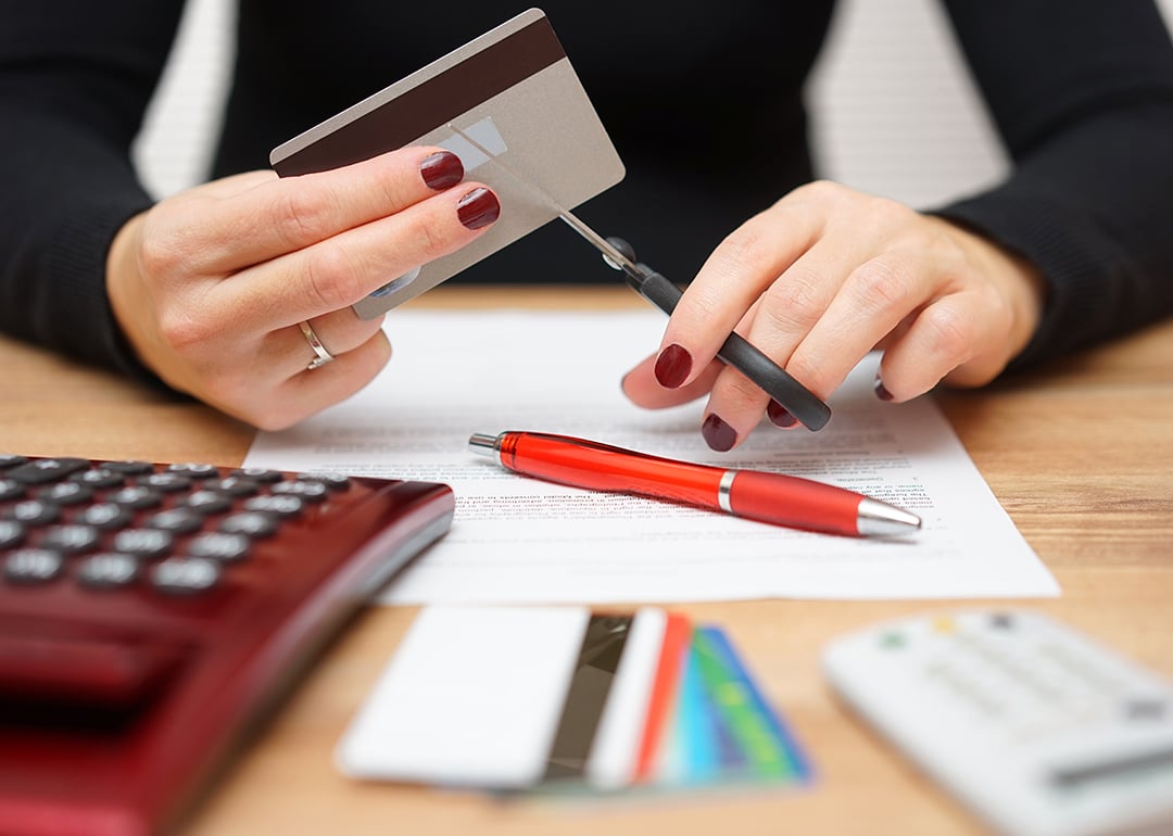 A woman cutting one of her credit cards in half.