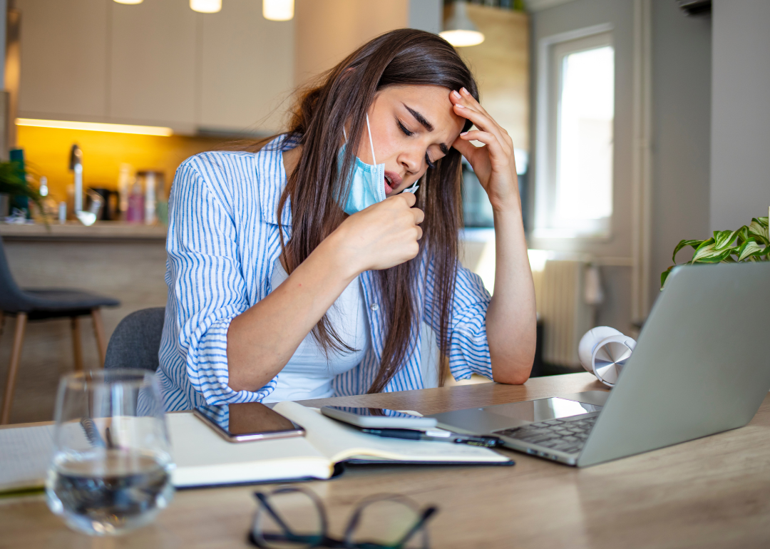 Woman working on a laptop pulls mask down after feeling breathless