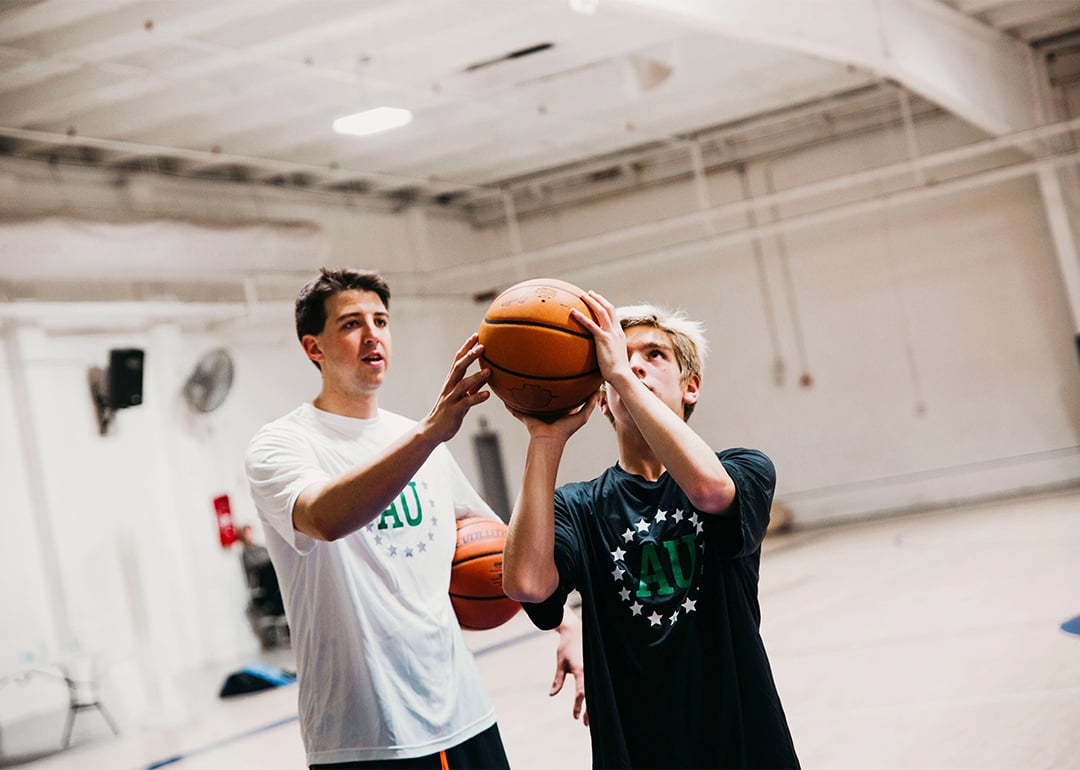 A coach showing a teen a basketball skill.