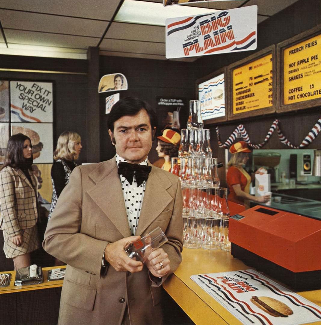 A man in a suit holding a glass inside of a Burger King