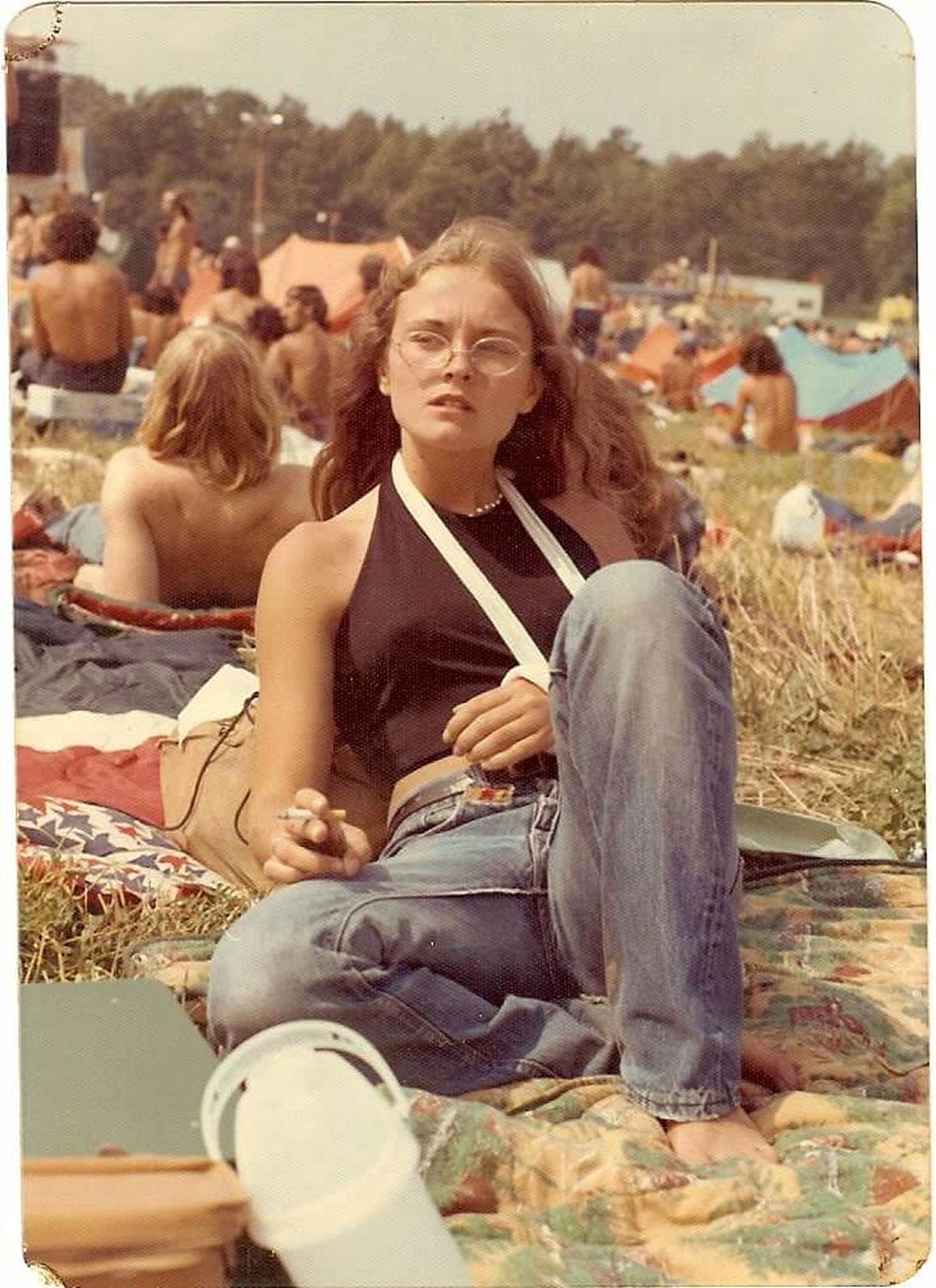 A young woman with her arm in a sling laying in a field at a concert