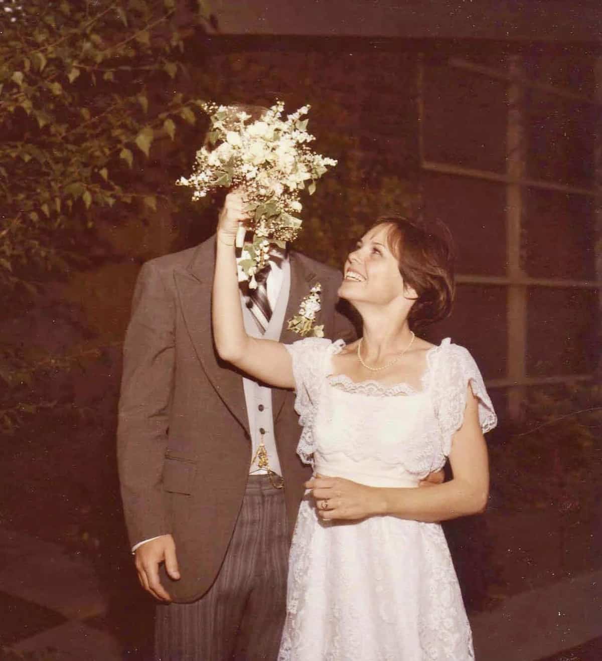 Bride holding her bouquet over her husbands face 