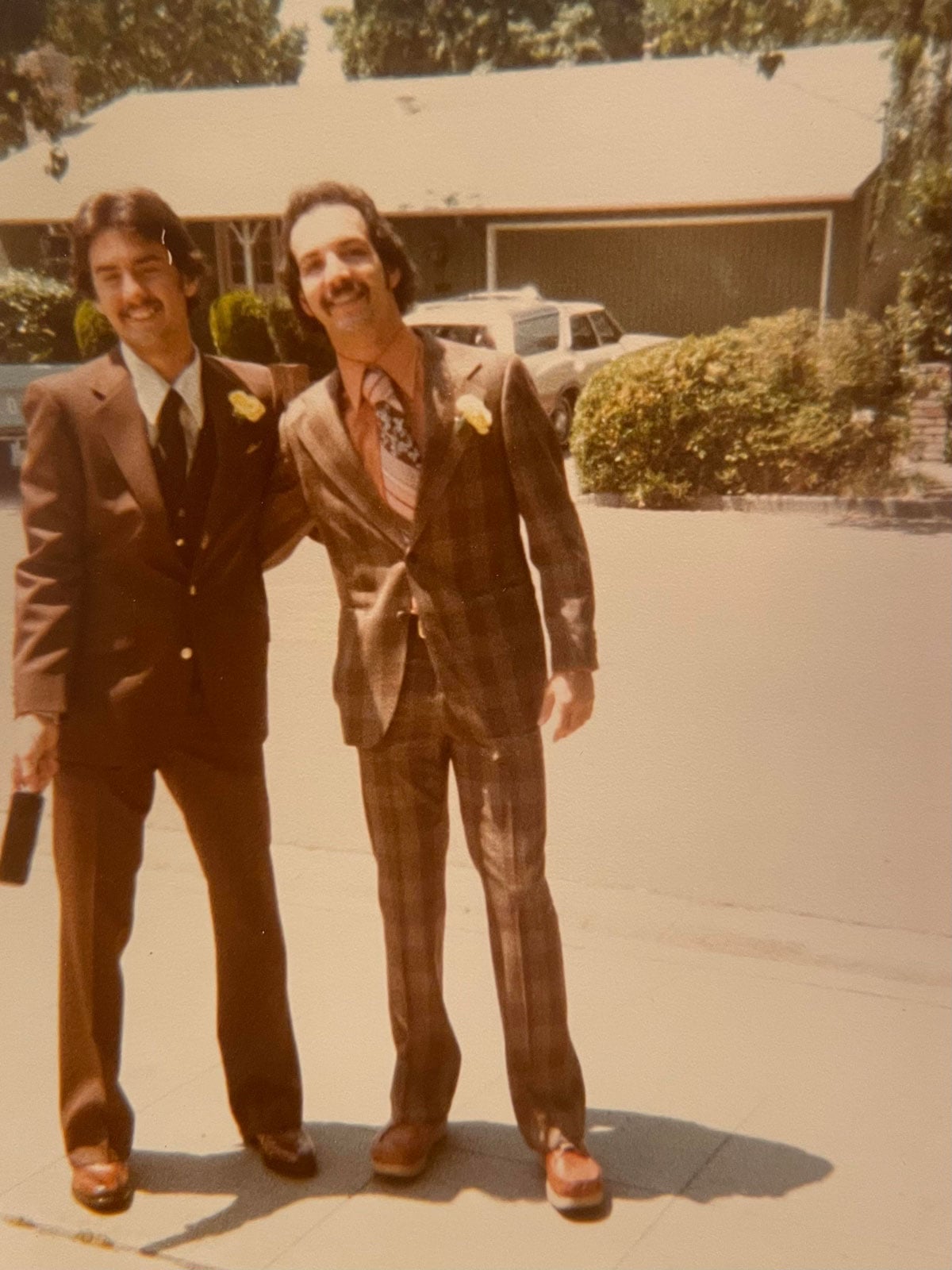 Two young men in suits with corsages
