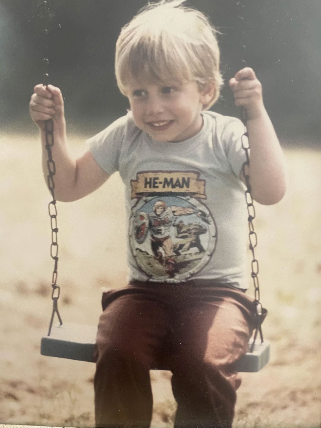 Little boy wearing a He-Man shirt on a swing