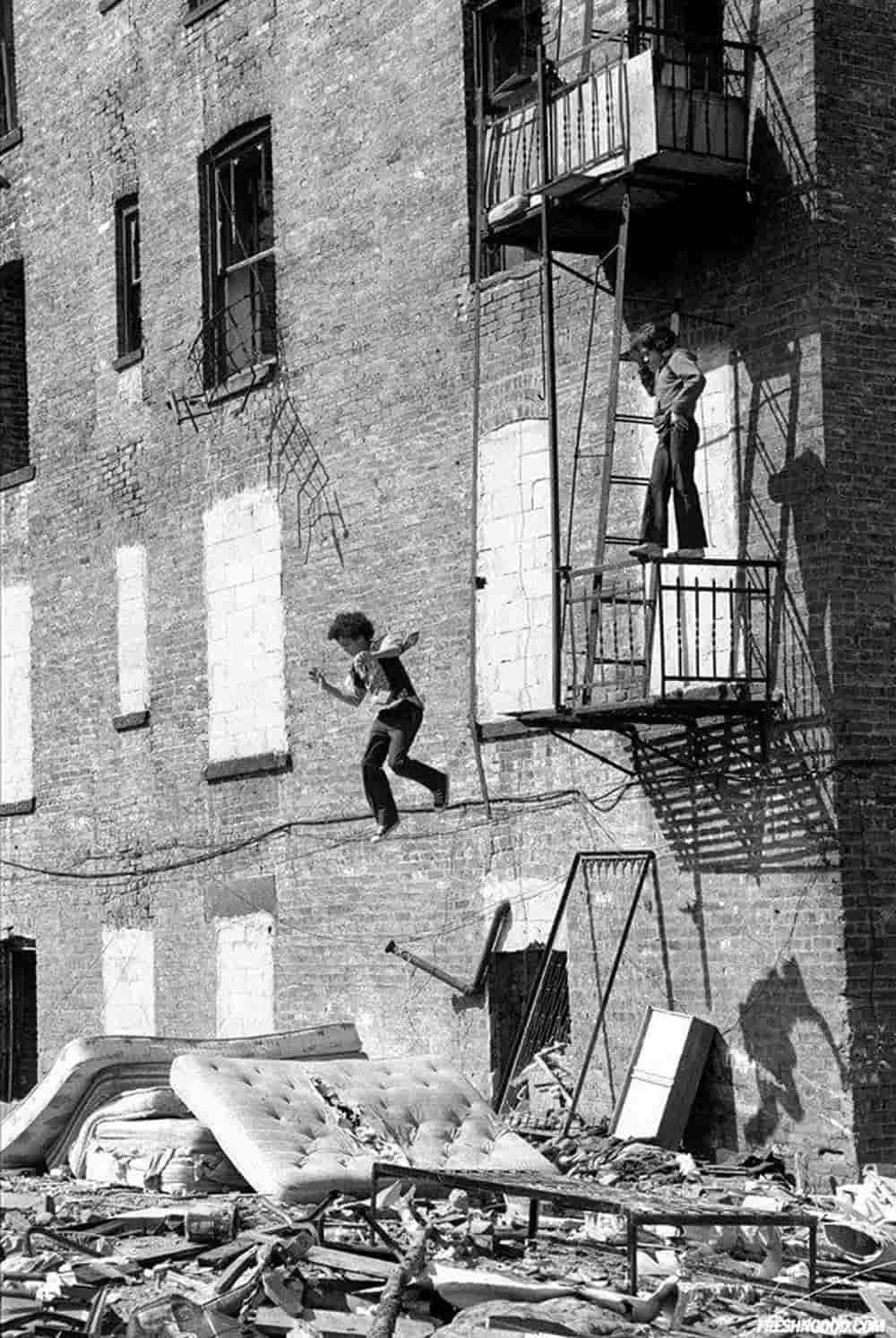 Black and white photo of a kid jumping from a fire escape