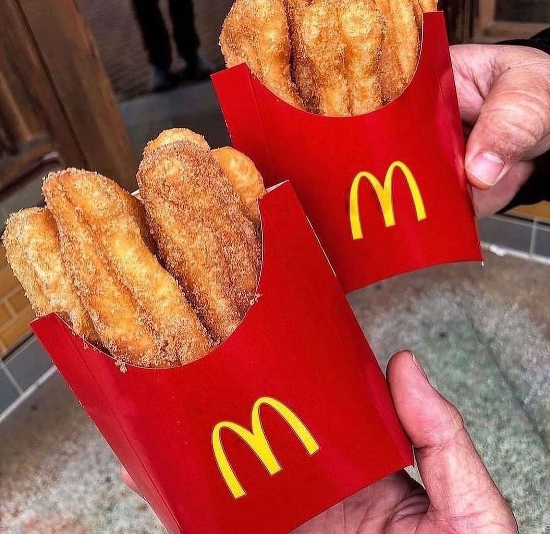 Hands holding two containers of donut sticks