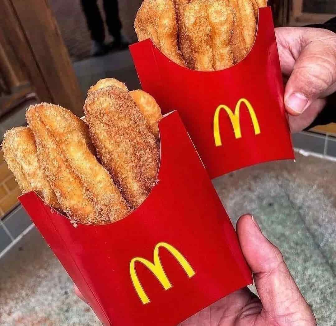 Hands holding two containers of donut sticks