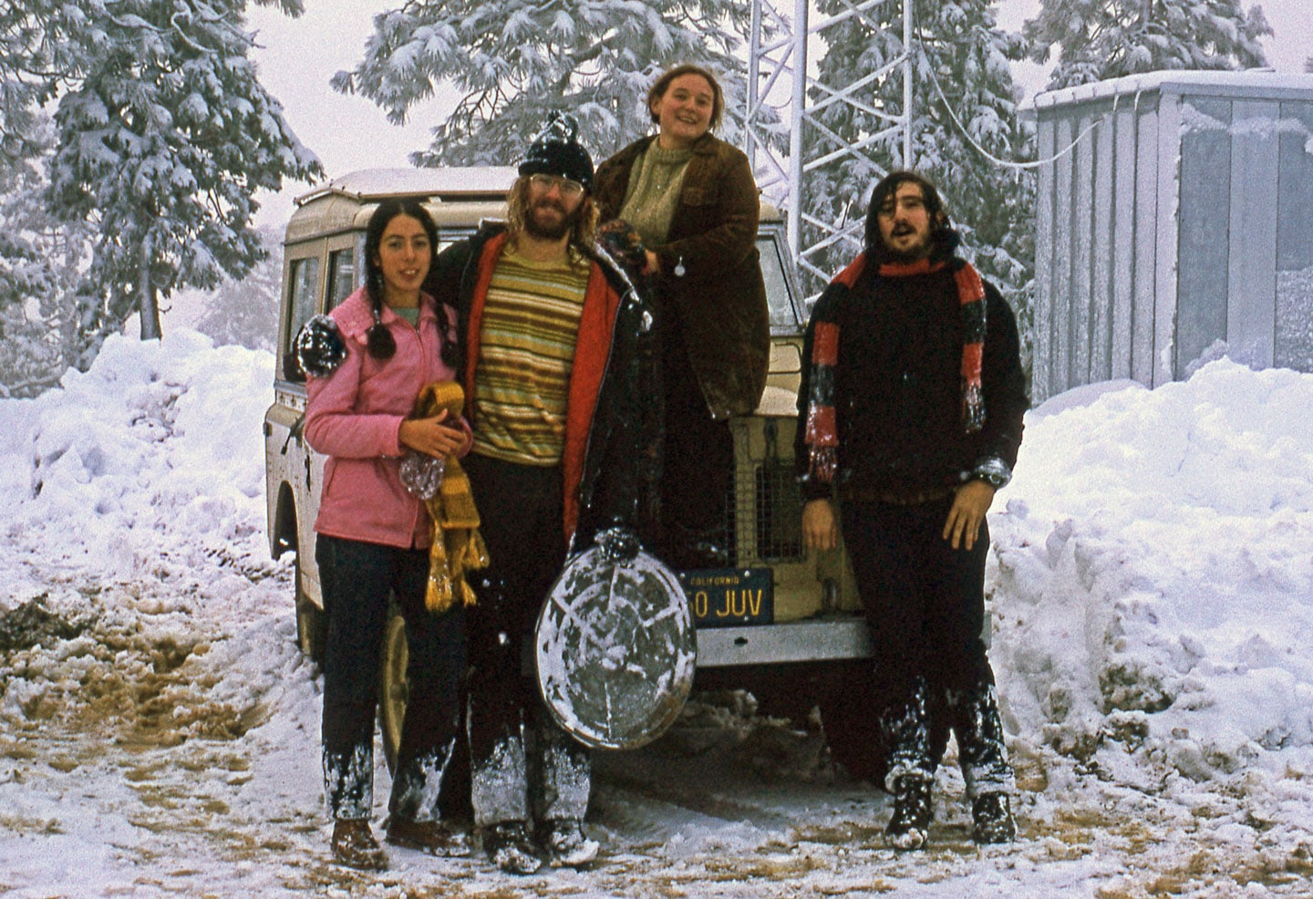 Four friends standing around in the snow 