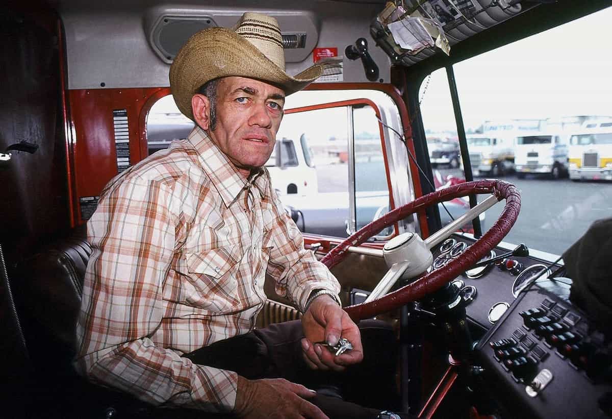 Photograph of a man in a cowboy hat sitting behind the wheel of a big rig