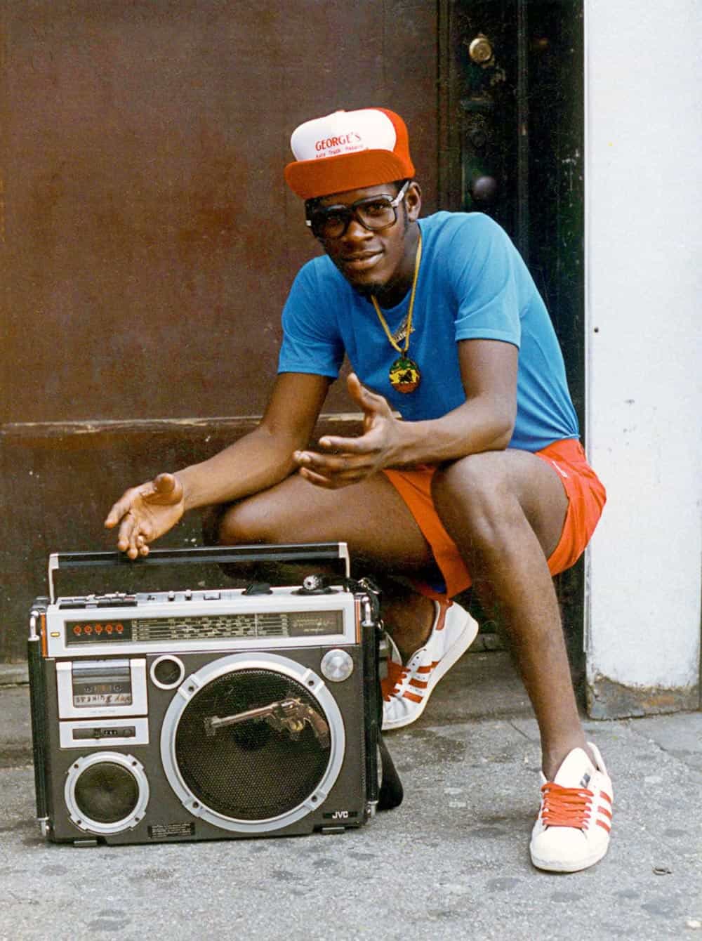 A man leaning over his boombox on the sidewalk