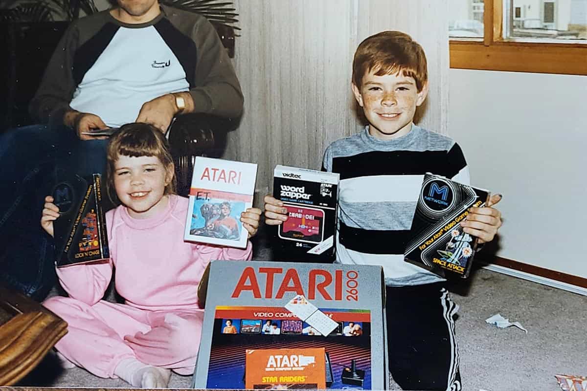 Two kids holding up their Atari games and the new Atari console