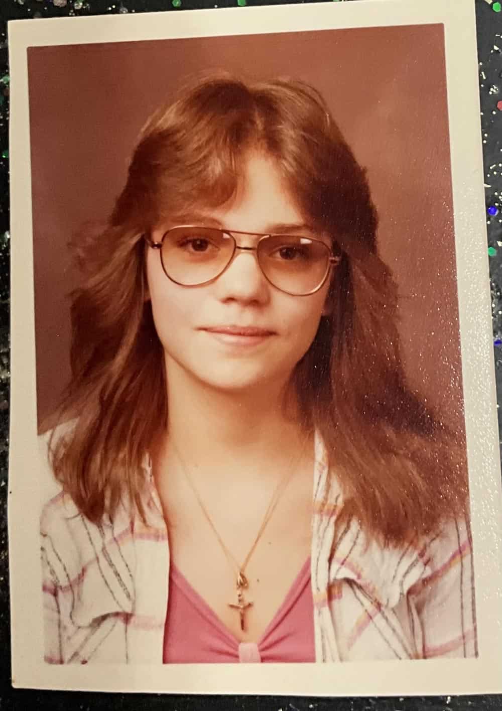 High school photo of a young woman with cool glasses and a cross ncklace