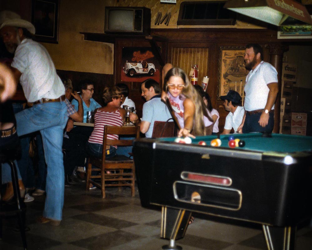 Woman playing pool in a fairly busy bar