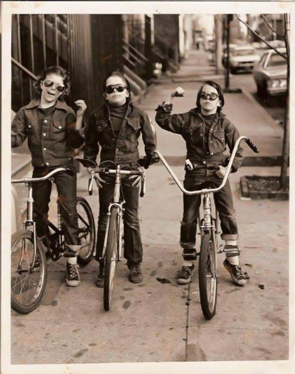 Three kids on bikes wearing sunglasses and denim jackets
