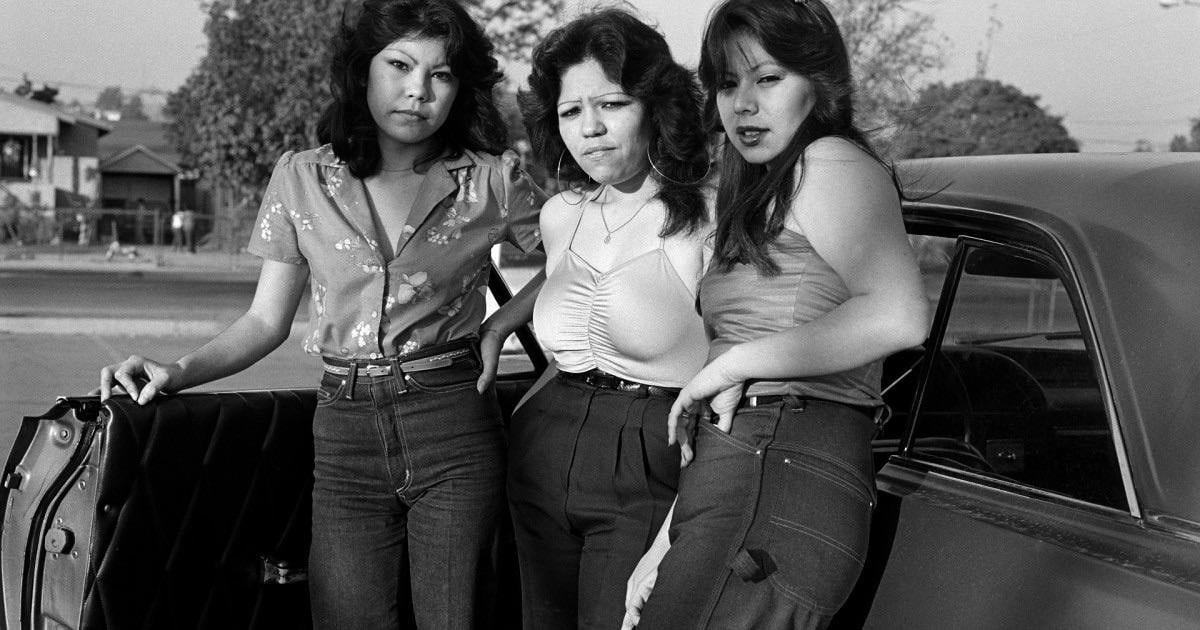 Three women pose for a photo next to a car