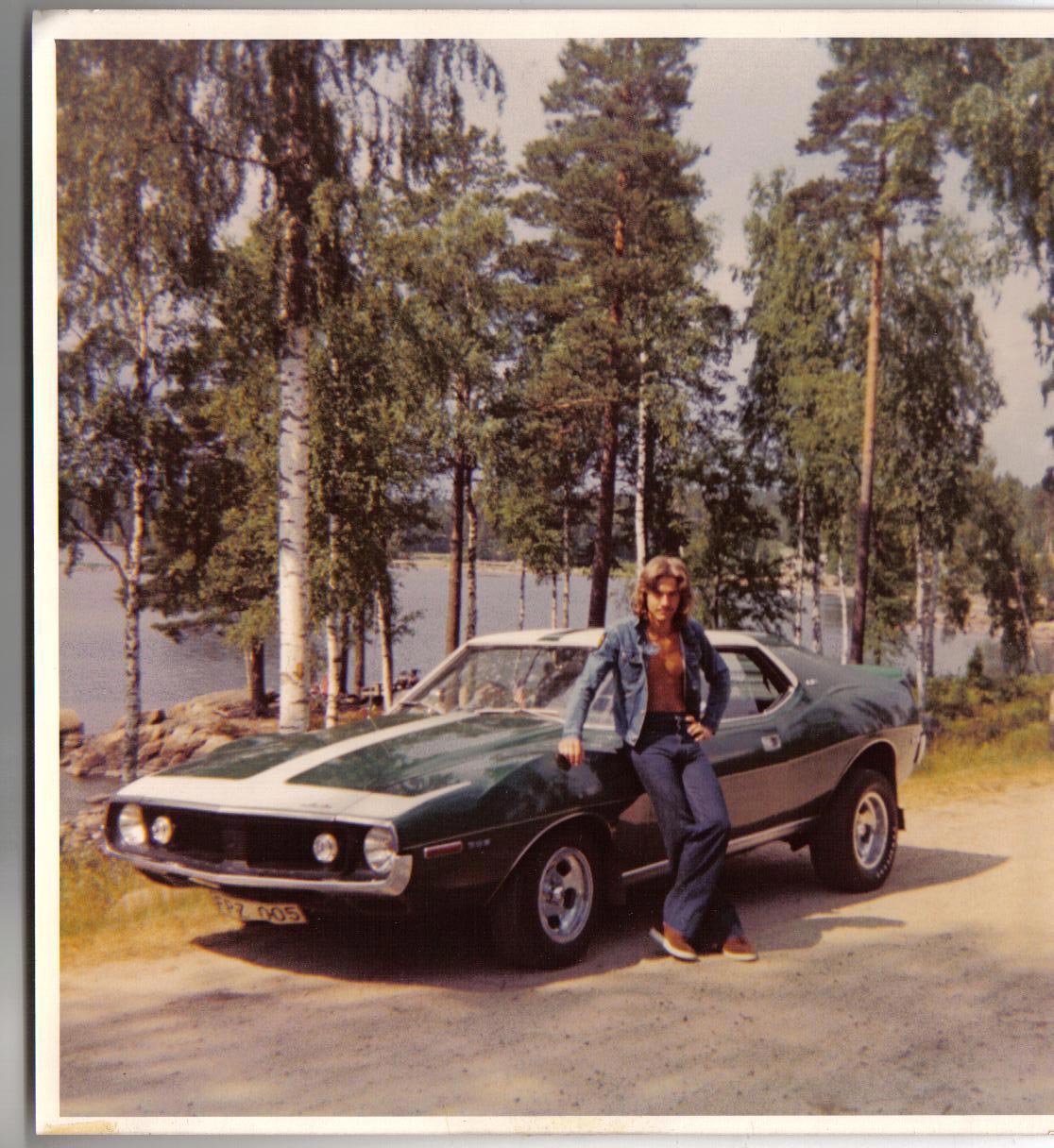 Man leaning against his green car in the 1970s