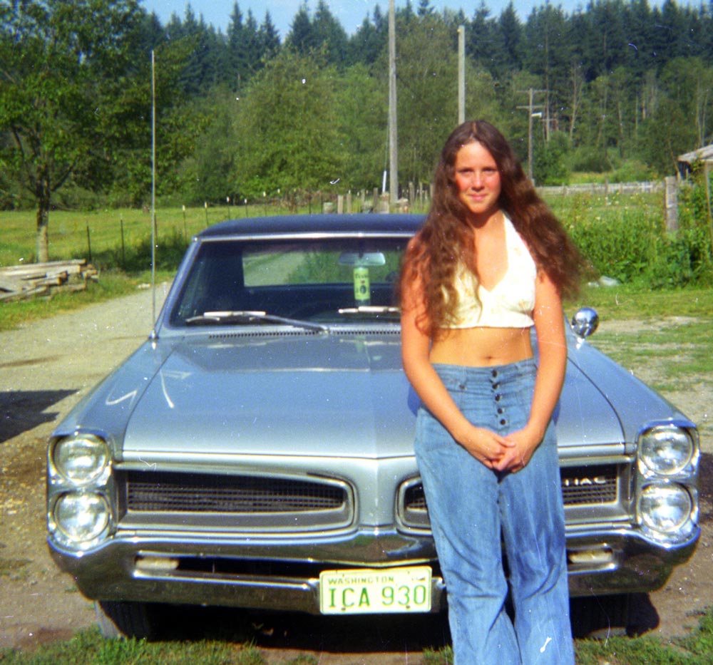 A young woman standing in front of her GTO car
