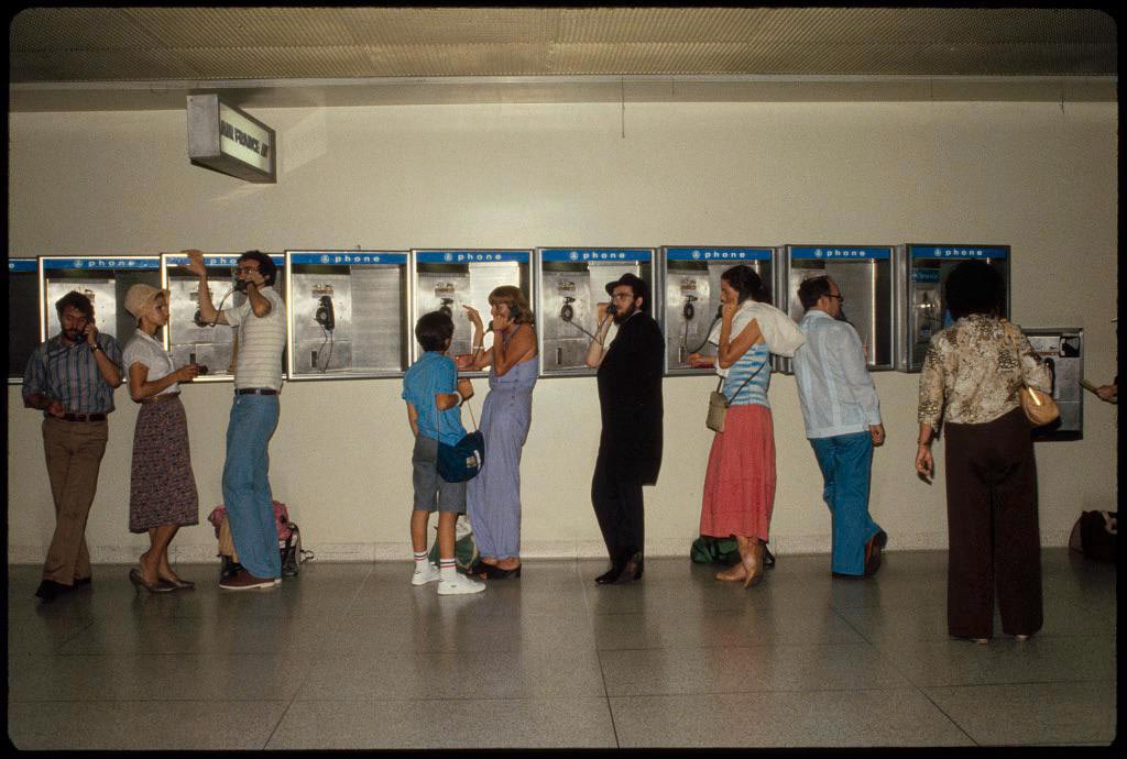 Various people talking on a wall of payphones at LaGuardia airport