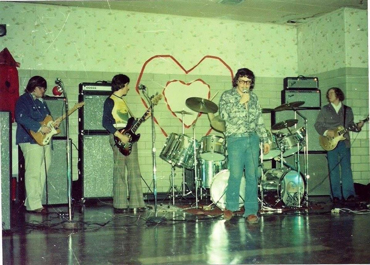 Four guys performing in a band at a school dance