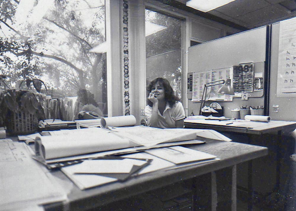 A young woman sitting at a desk looking at the camera