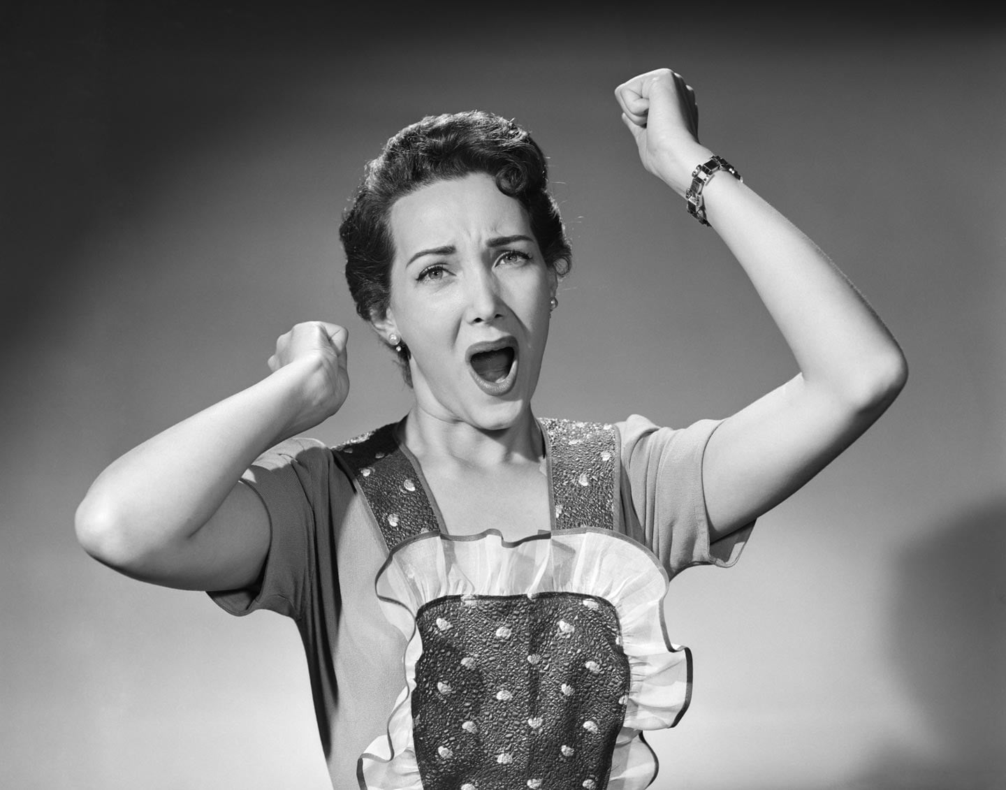 Woman in the 1950s wearing an apron raising her hands in frustration