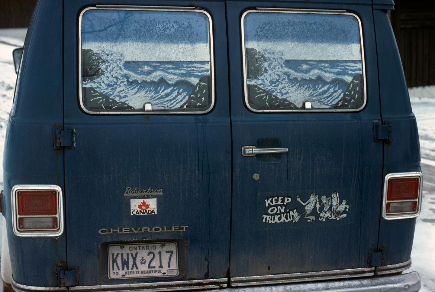 Vintage photo of a blue van with a 'Keep on Truckin' sticker