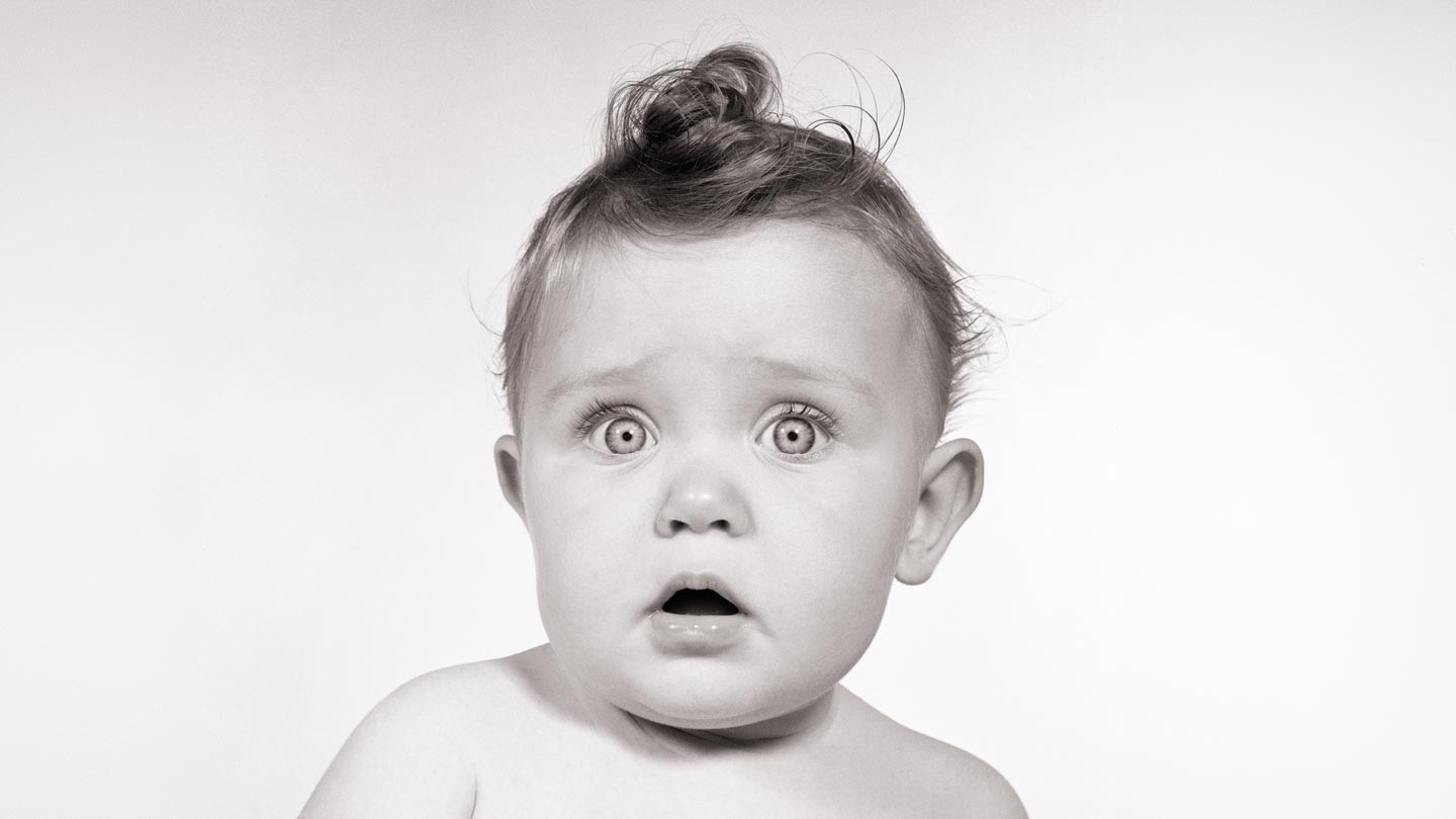 Wide-eyed baby from the 1950s looking at the camera.