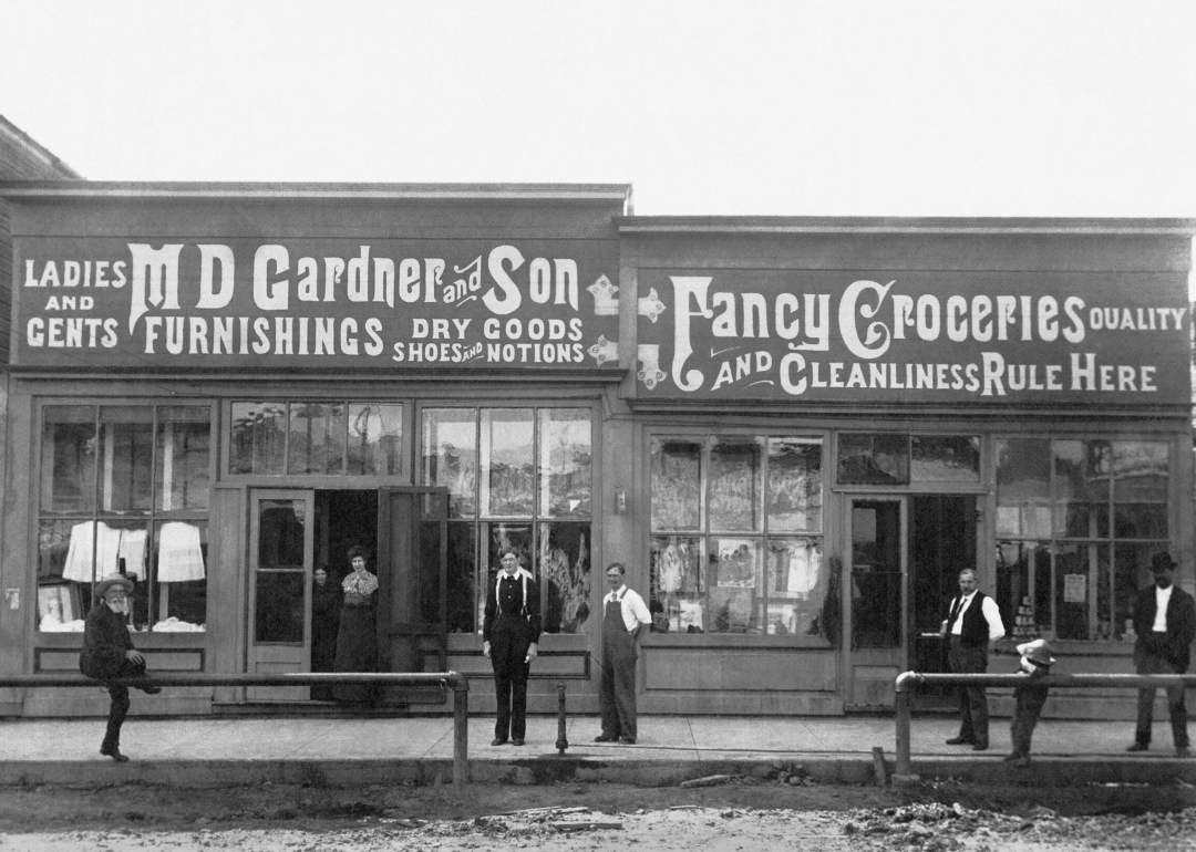 People standing in front of a general store with painted signs