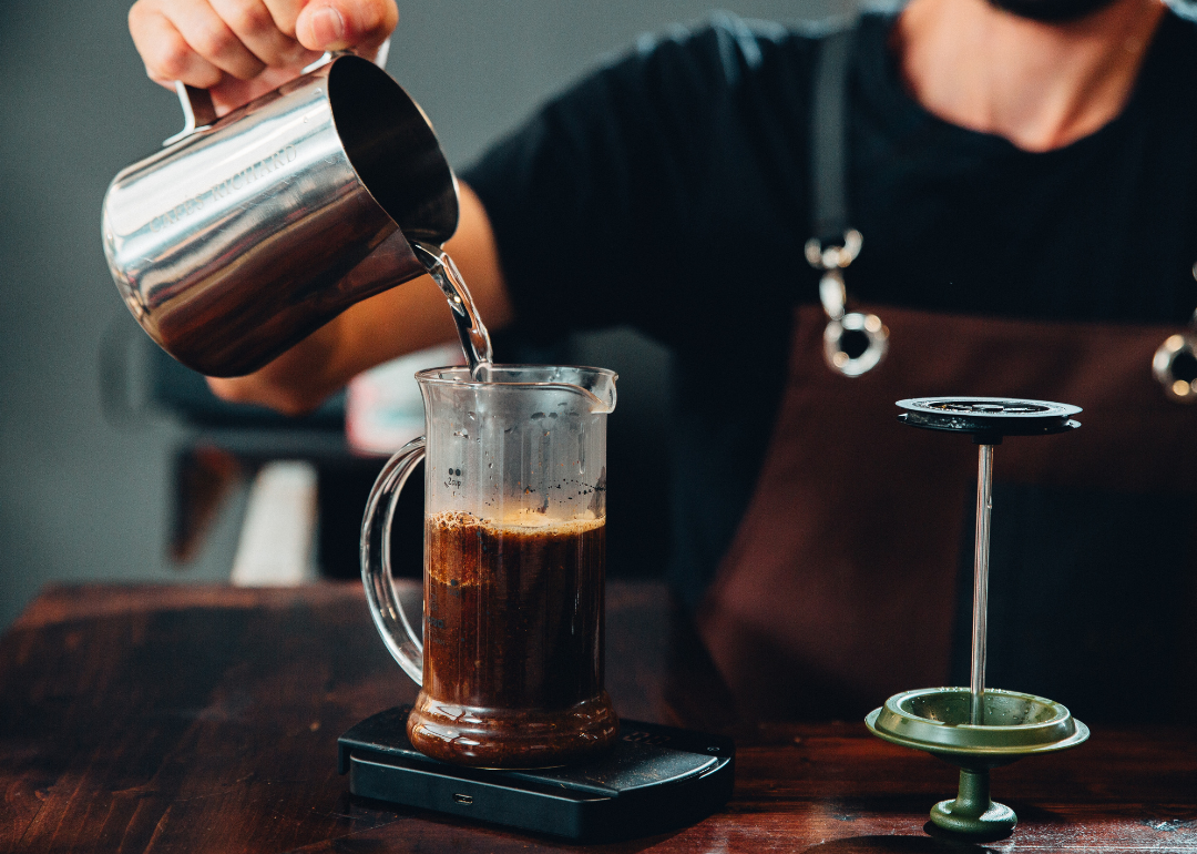 Barista pouring water in French press.