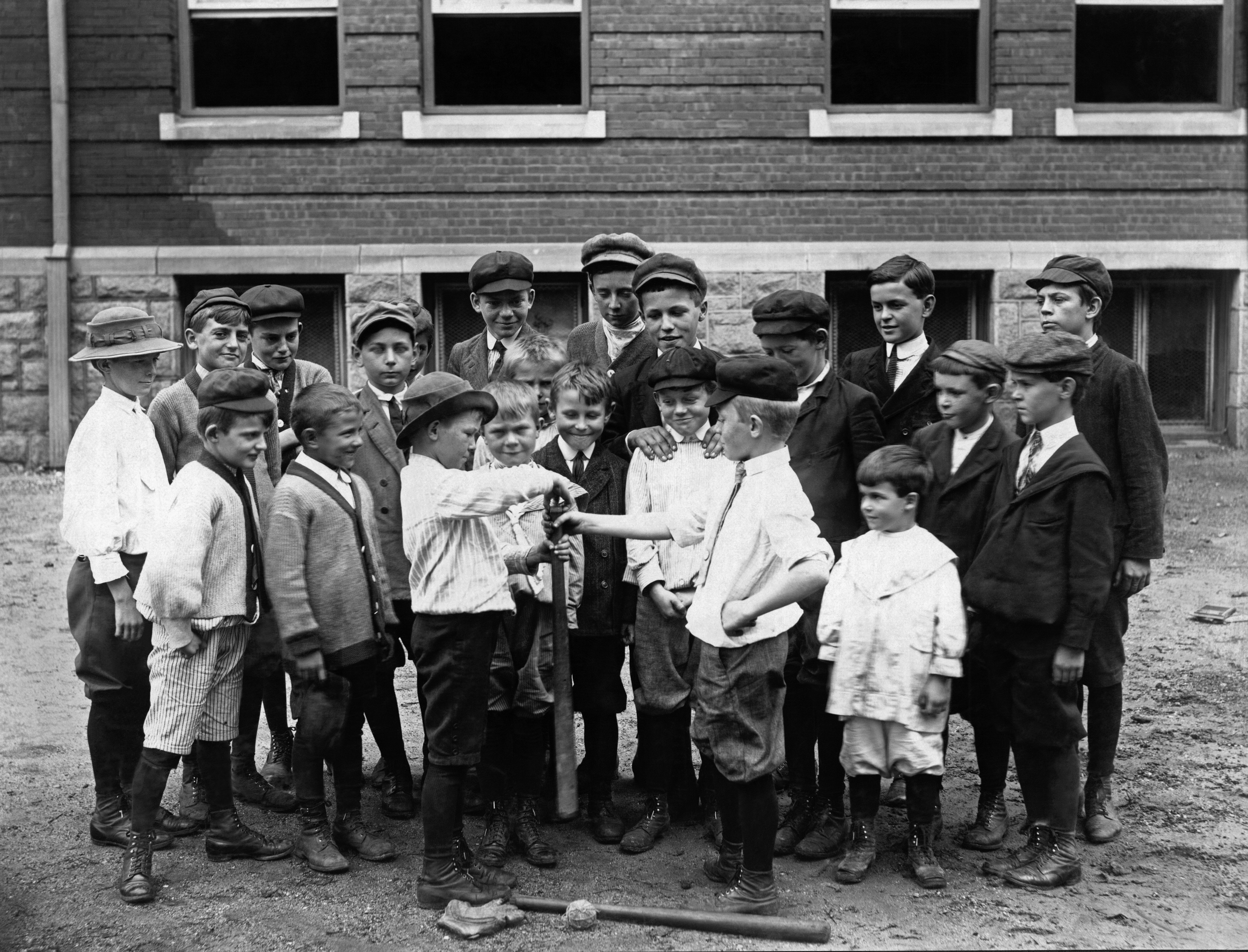 Group of school children with hands on a bat preparing for baseball game.