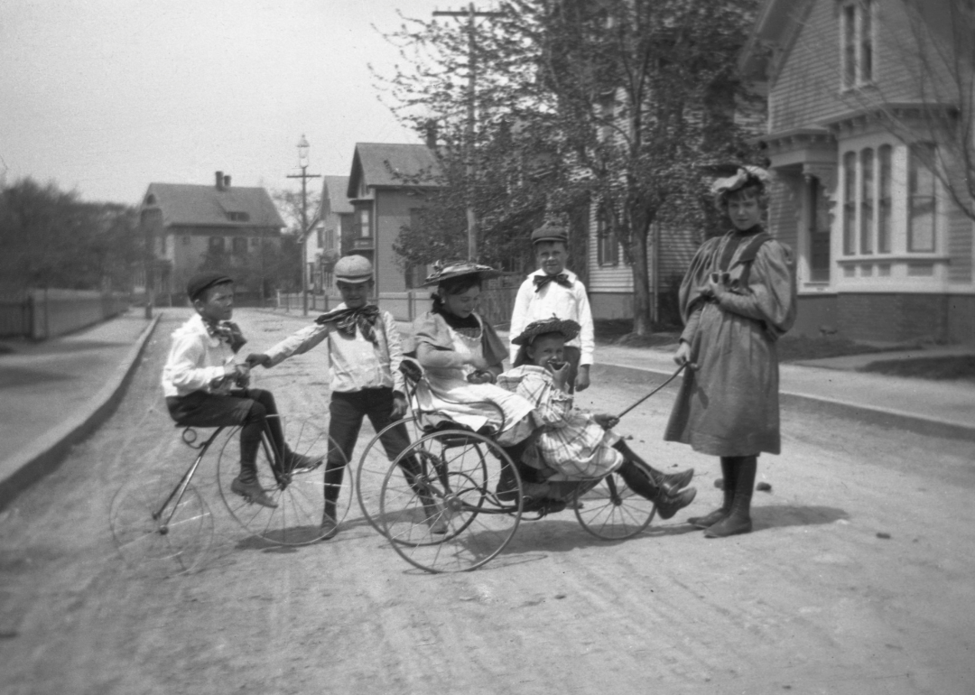 Group of children playing on side street with Velocipede and tricycle